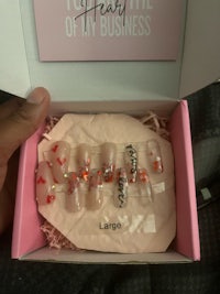 a person holding a pink box with a lot of nails in it